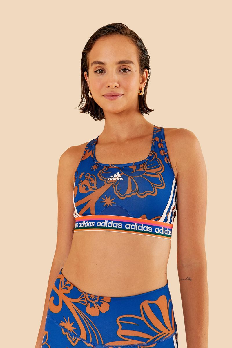 Modelo vistiendo top Adidas Boho Flower Real con estampado floral azul y naranja, vista frontal.