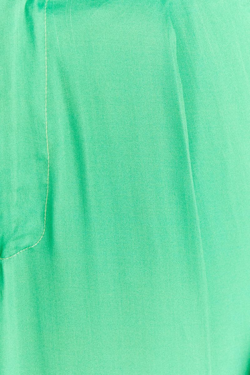 Primer-plano-del-acabado-del-dobladillo-aplicado-en-el-pantalon-flare-de-saten-verde-claro.