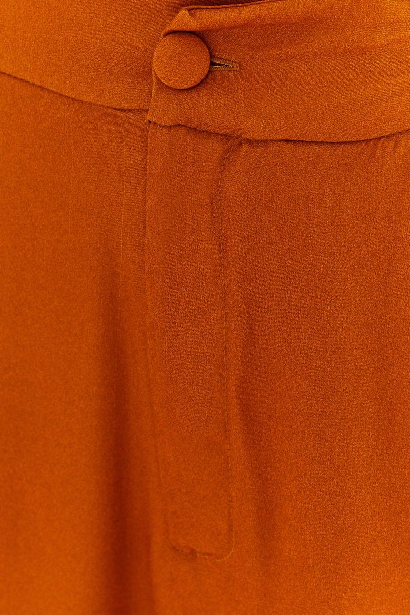 Close-up-de-la-tela-de-saten-en-tono-ocre-del-pantalon-flare.