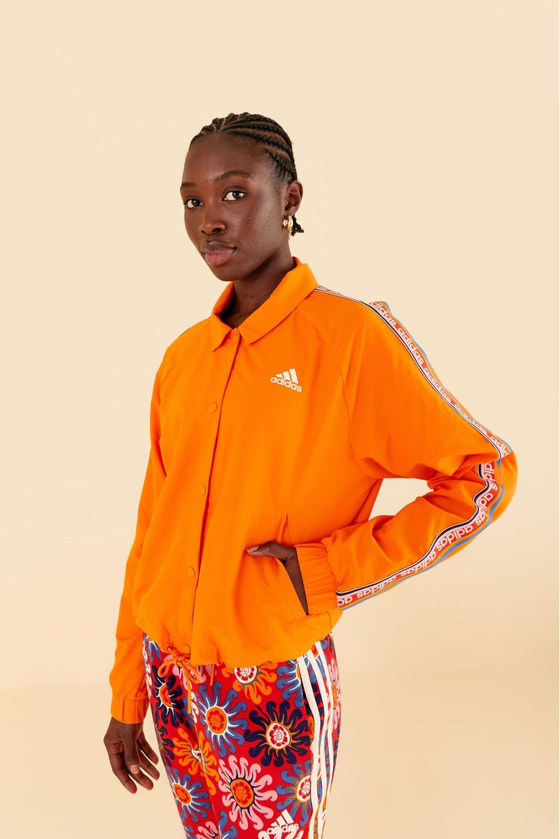 Modelo usando abrigo Adidas Sunny Day Orange con estampado geométrico y pantalones estampados.