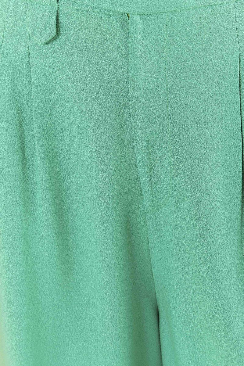 Acercamiento al tejido de viscosa creponada del pantalón verde claro.