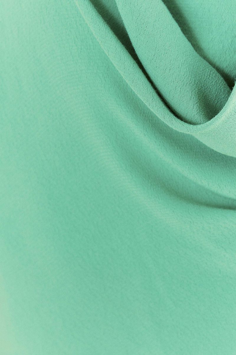 Vista lateral de la blusa degagê verde con tirantes ajustables.