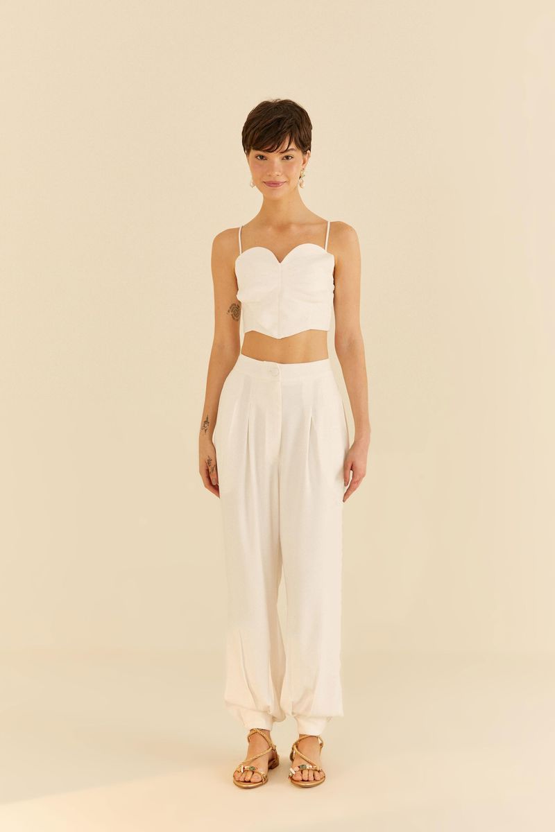 Modelo usando pantalón estilo zanahoria con pliegues y top blanco.