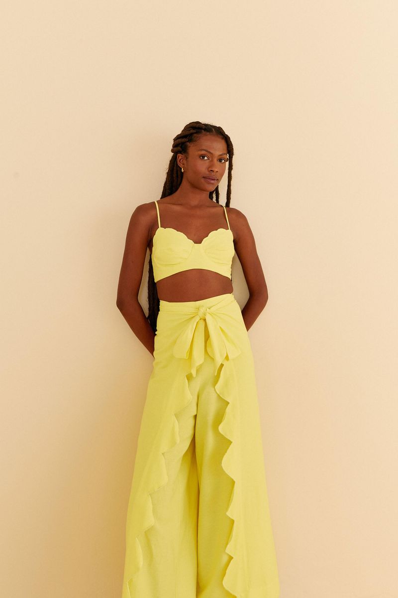 Modelo usando pantalón amarillo con detalle de amarre y acabado vertical de nube en el frente.