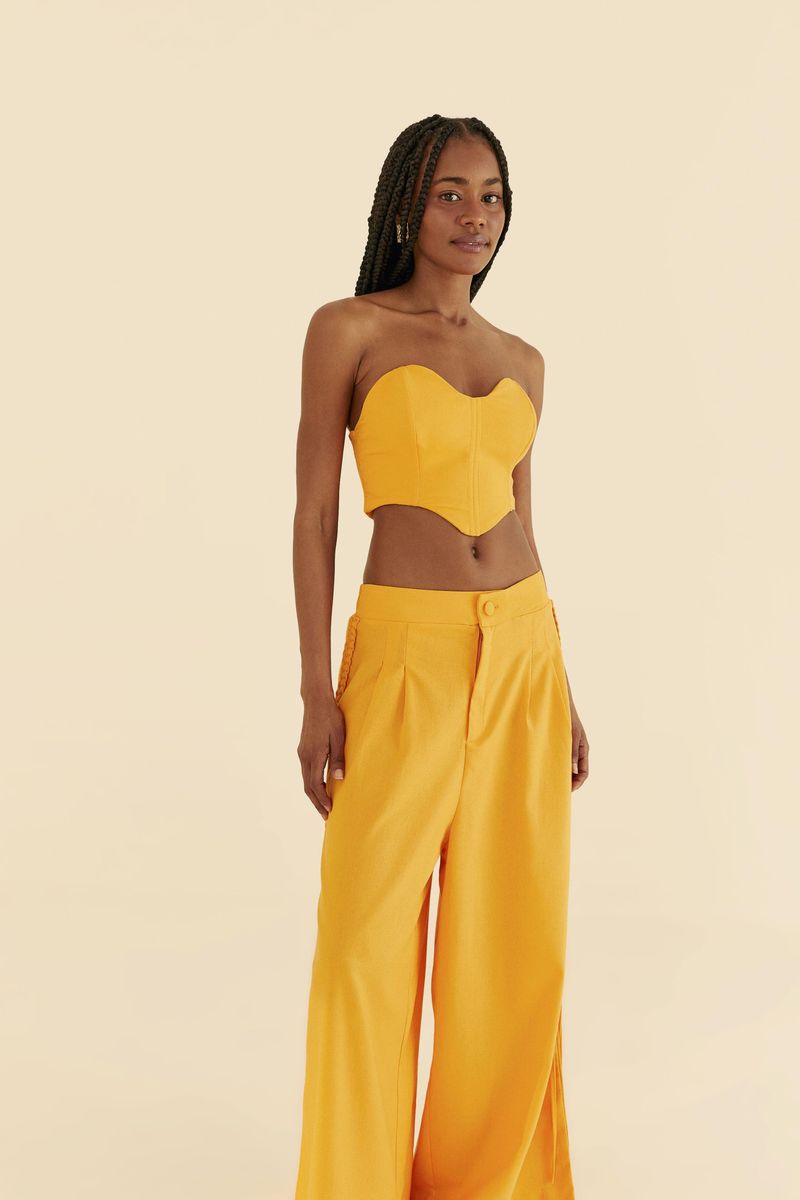 Modelo-vistiendo-pantalon-largo-de-lino-amarillo-con-detalles-trenzados-en-los-laterales-y-aberturas-en-el-dobladillo.