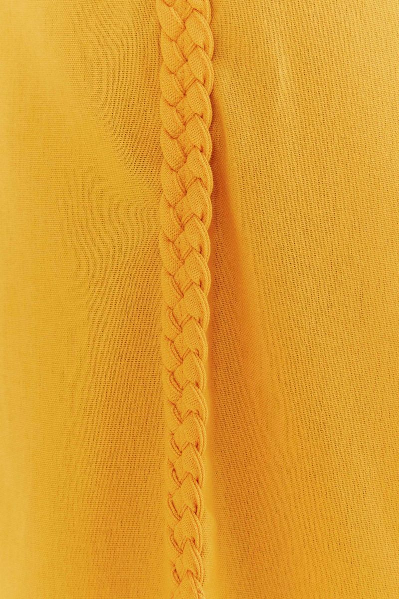 Primer-plano-del-detalle-trenzado-en-el-lateral-del-pantalon-amarillo.