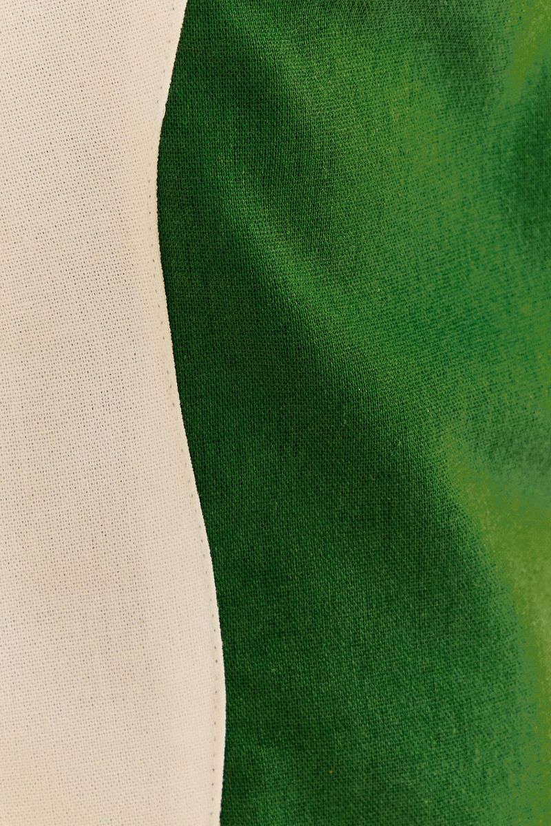 Acercamiento-al-corte-ondulado-en-el-lateral-del-pantalon-de-pierna-ancha-bicolor-en-verde-y-blanco.