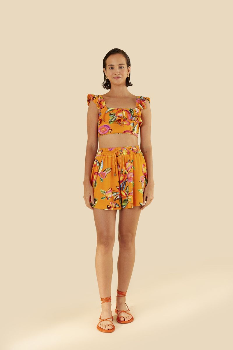 Imagen de un top estampado tropical con volantes y escote cuadrado, visto de lado.