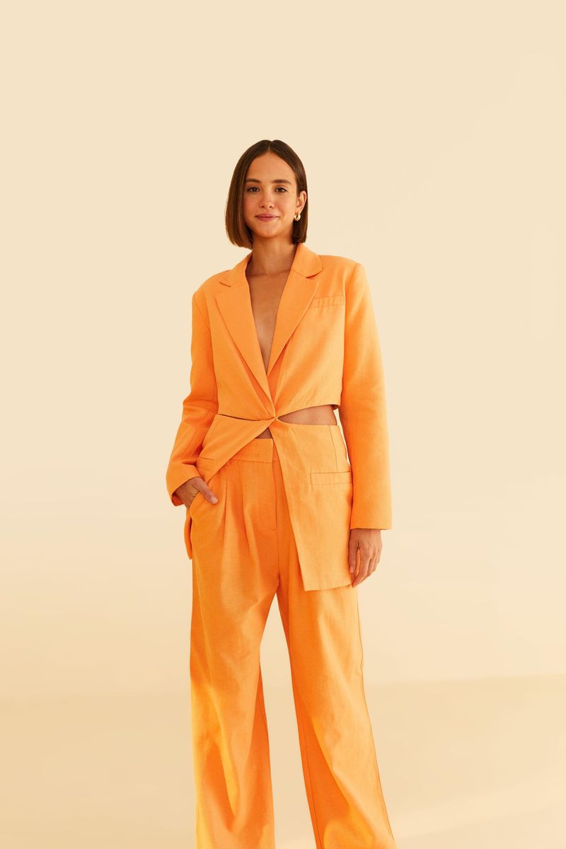 Imagen de una modelo vistiendo un pantalón de sastrería naranja con blazer a juego, vista frontal.