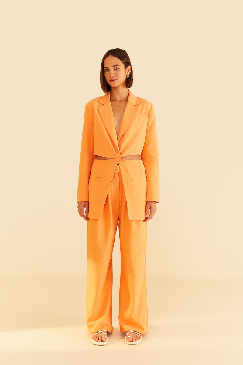 Imagen de una modelo vistiendo un pantalón de sastrería naranja con blazer a juego, vista trasera.