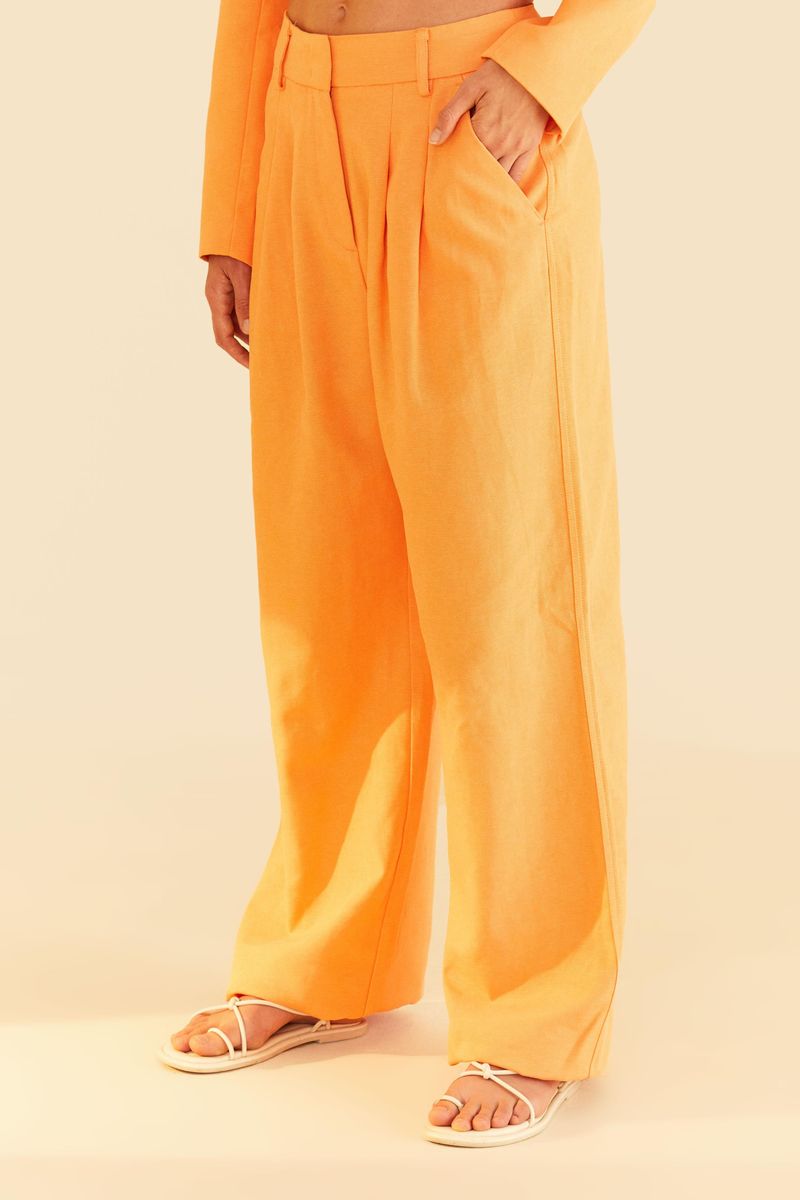 Detalle del pantalón de sastrería naranja mostrando la cintura y los bolsillos laterales.