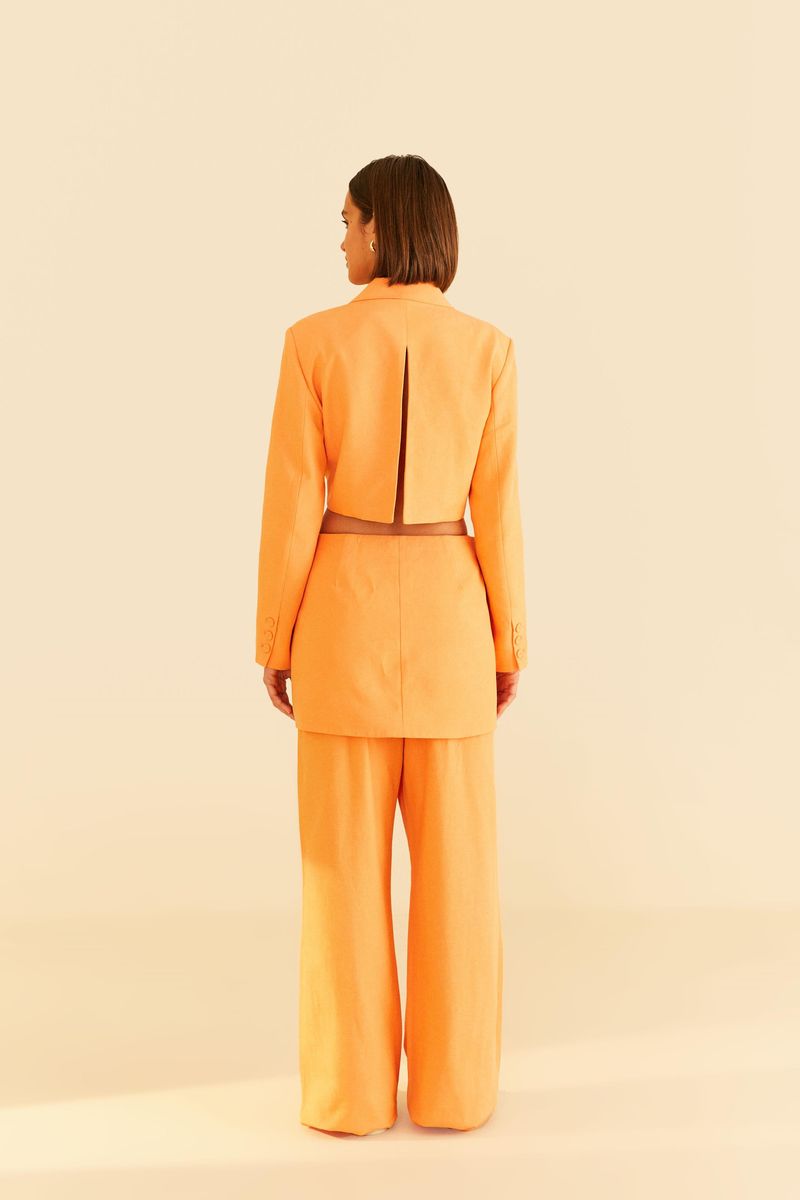Vista trasera del pantalón de sastrería naranja con blazer a juego.
