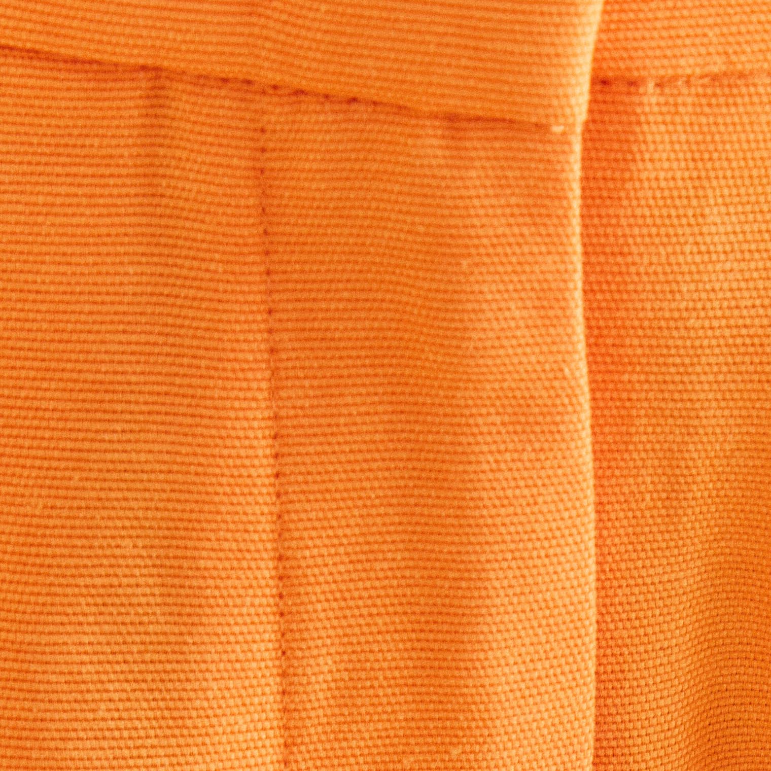 Acercamiento de la cintura del pantalón de sastrería naranja mostrando los pasadores y el acabado.