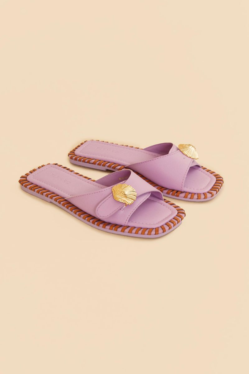 Sandalia plana slipper lila con detalle metálico en forma de concha vista desde arriba.