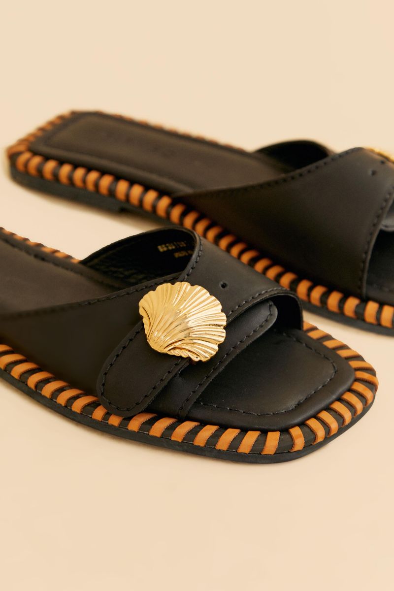 Sandalia-Bajita-Slipper-en-tono-lila-con-detalle-metalico-en-forma-de-concha-vista-inferior.