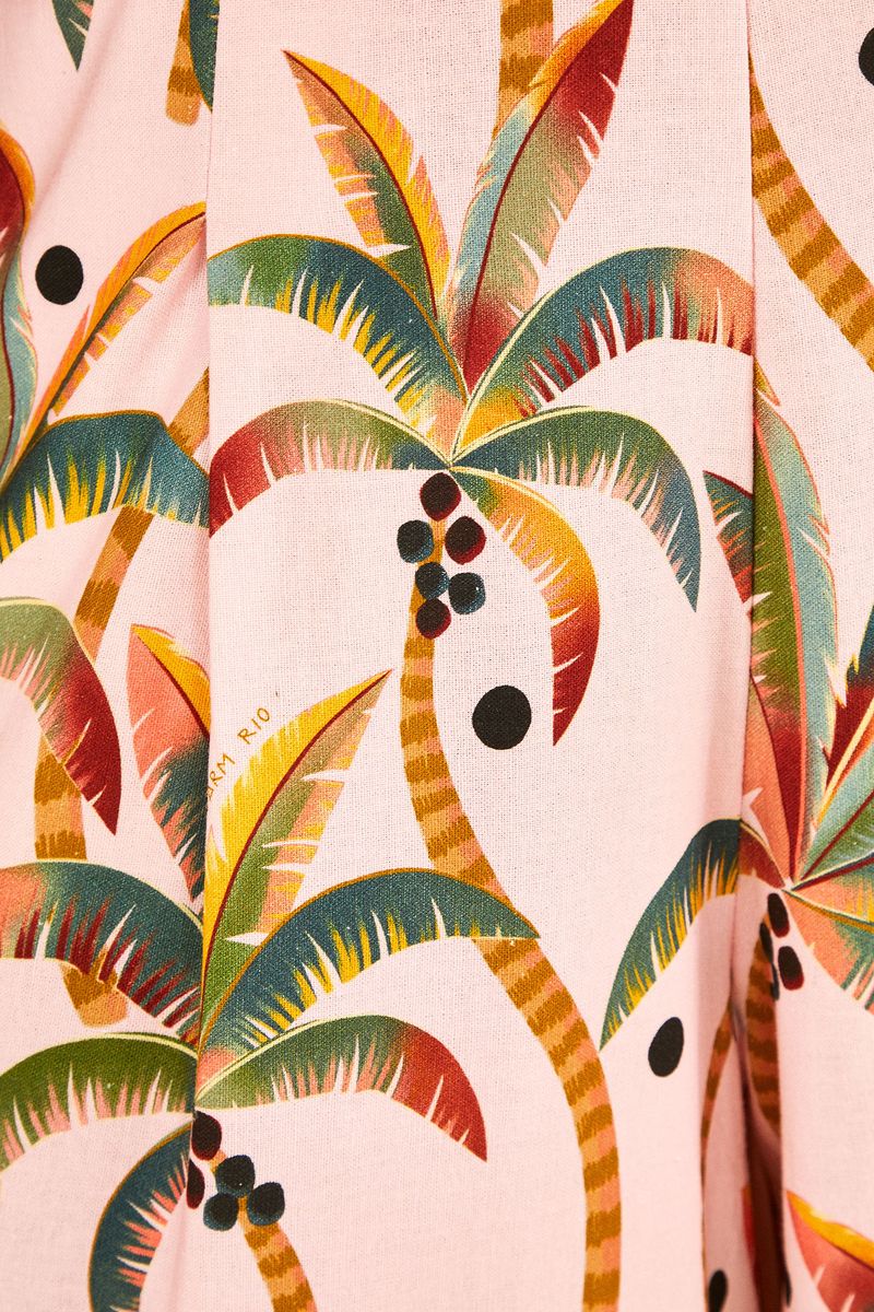 Primer-plano-del-estampado-tropical-del-macacon-Samba-de-los-Coqueiros-con-palmeras-y-fondo-rosado-claro.