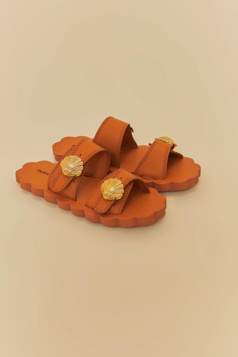 Sandalias caramelo con detalle de concha dorada vistas de lado.