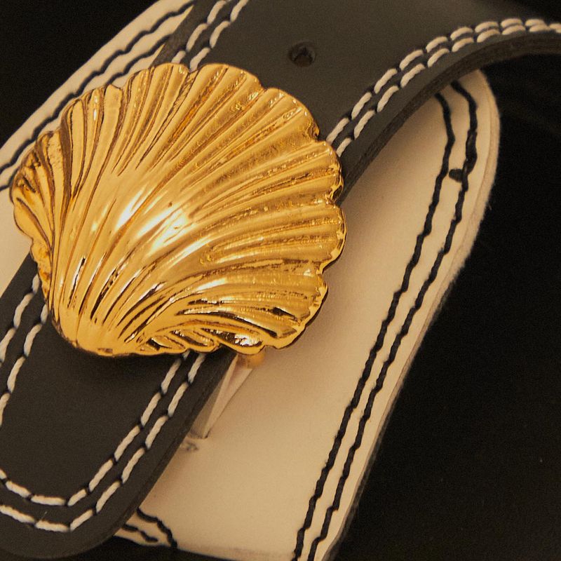 Close-up del detalle dorado en forma de concha en las sandalias Sand Slide Concha Negro.