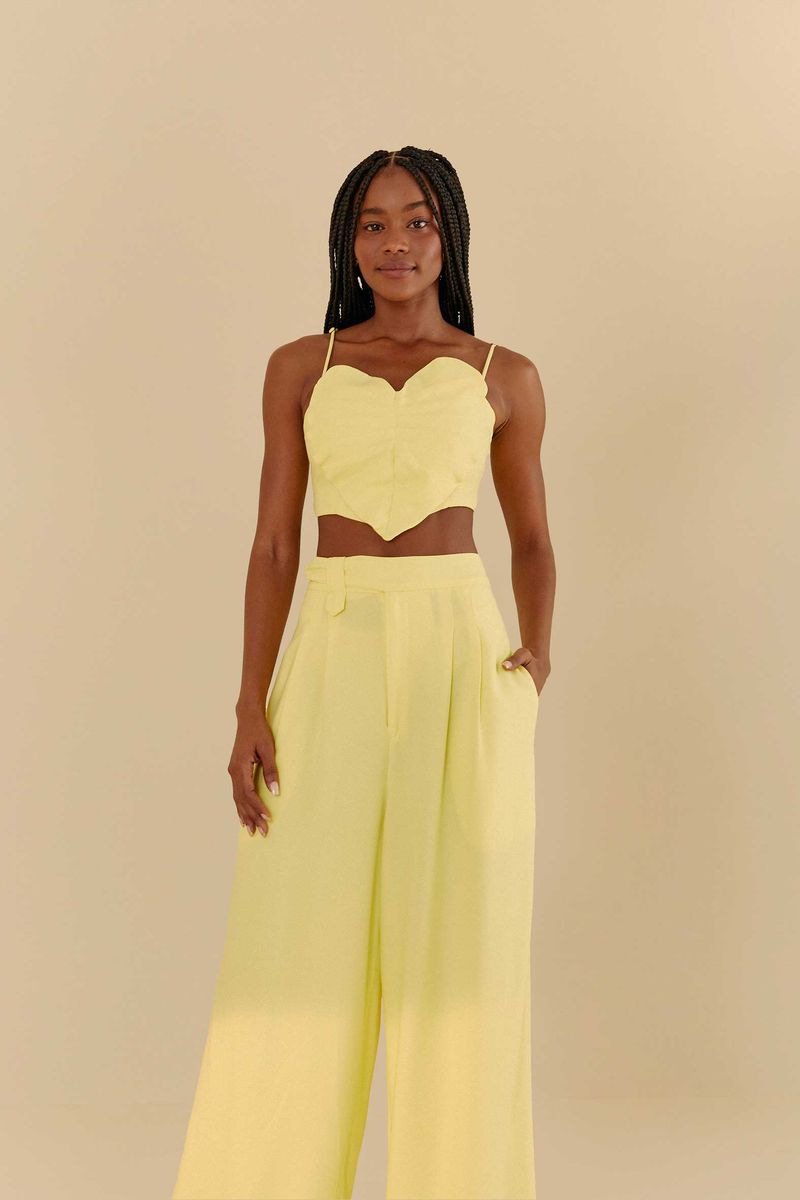 Modelo vistiendo pantalón recto amarillo con pliegues, vista frontal, destacando el ajuste en la cintura y el caimiento de las piernas