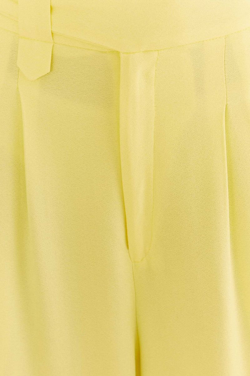 Acercamiento-al-tejido-y-pinzas-del-pantalon-recto-amarillo-claro.