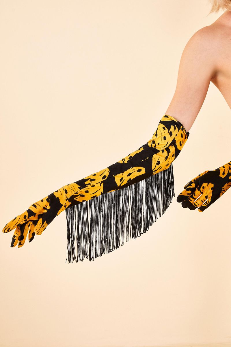 Imagen-de-una-persona-utilizando-el-guante-largo-estampado-con-bananas-en-fondo-negro-con-flecos-en-los-laterales-destacando-el-estilo-y-diseño-unico.