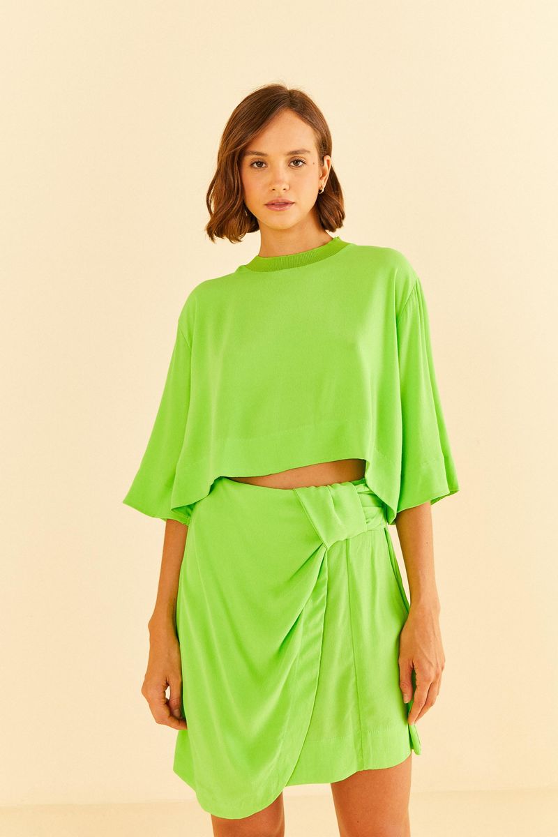 Modelo-usando-minifalda-verde-con-diseño-cruzado-y-detalle-plisado-vista-trasera.
