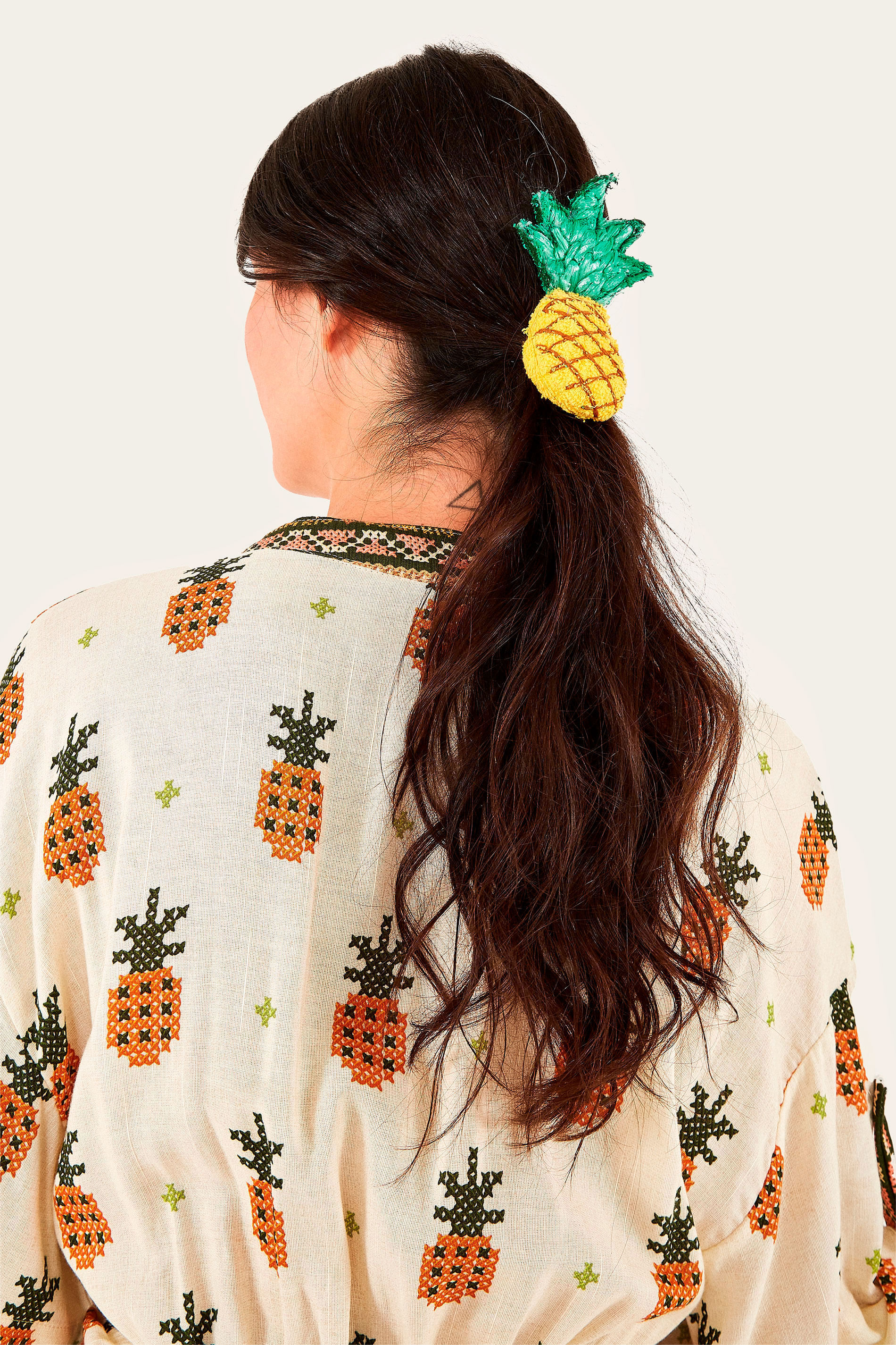 Sujetador-de-cabello-en-forma-de-piña-sobre-fondo-blanco-pieza-textil-con-elastico-negro-accesorio-femenino-colorido.