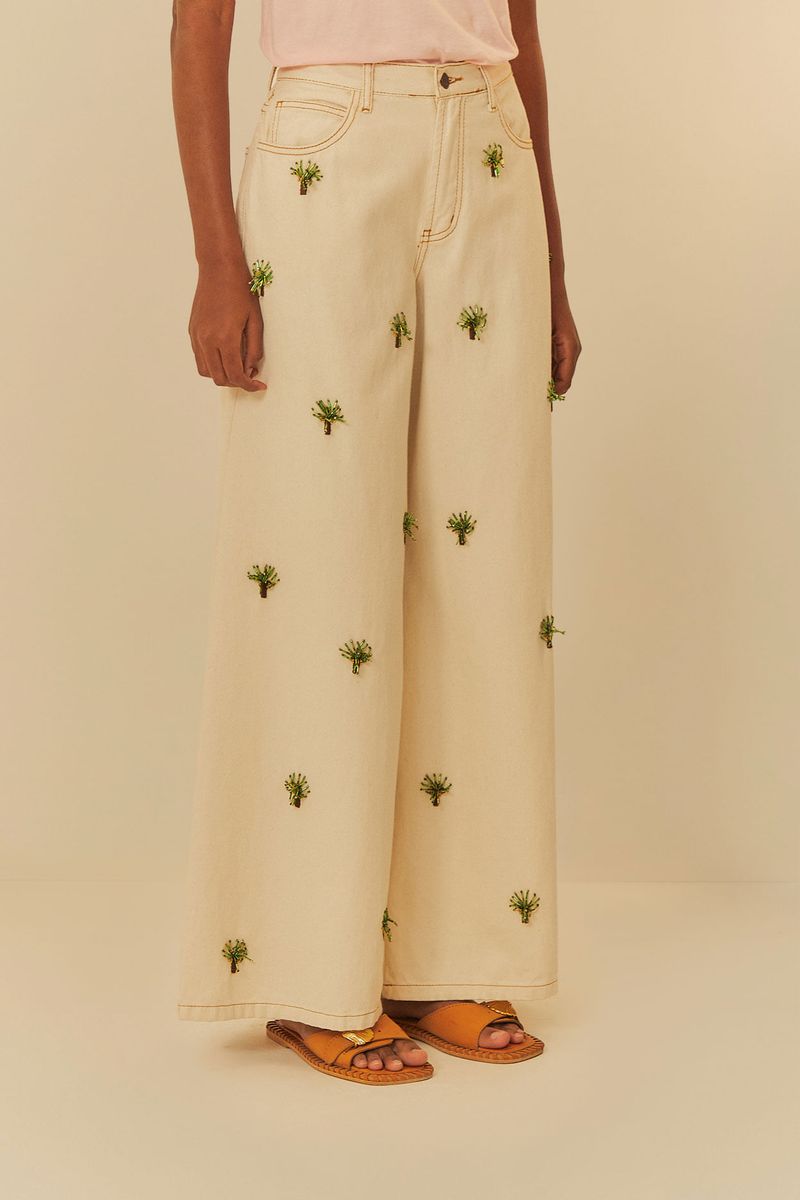 Vista trasera del pantalón beige ancho con bolsillos y bordados.