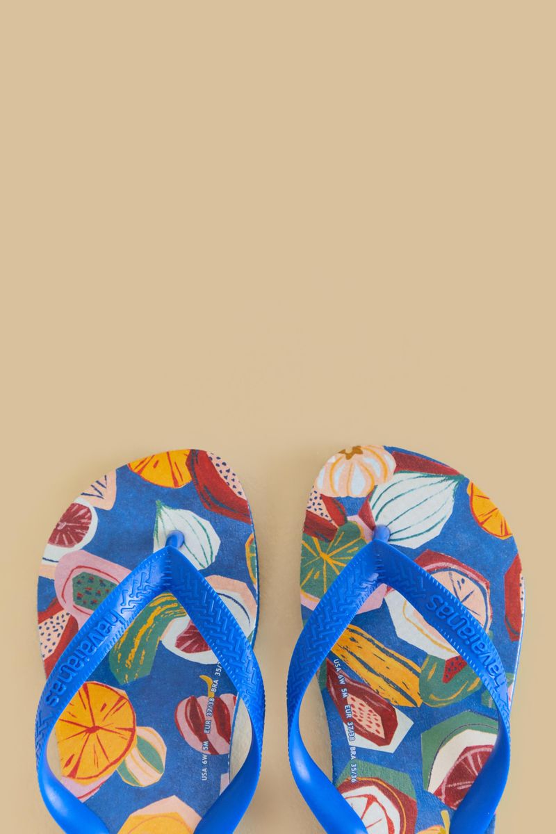 Detalle de las sandalias Havaianas mostrando el estampado de frutas tropicales y correas azules.