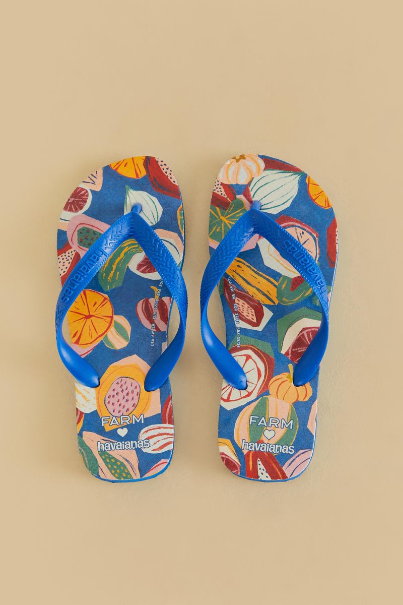 Vista frontal de las sandalias Havaianas con estampado vibrante de frutas tropicales y correas azules.