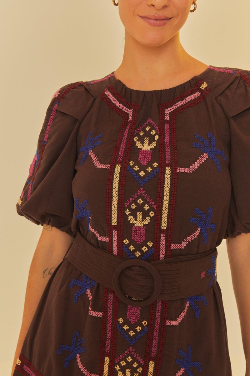 Detalle frontal del vestido mostrando los bordados vibrantes y el cinturón.