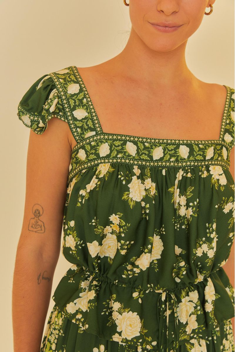 Primer plano de la blusa verde con estampado floral y volantes en los hombros.