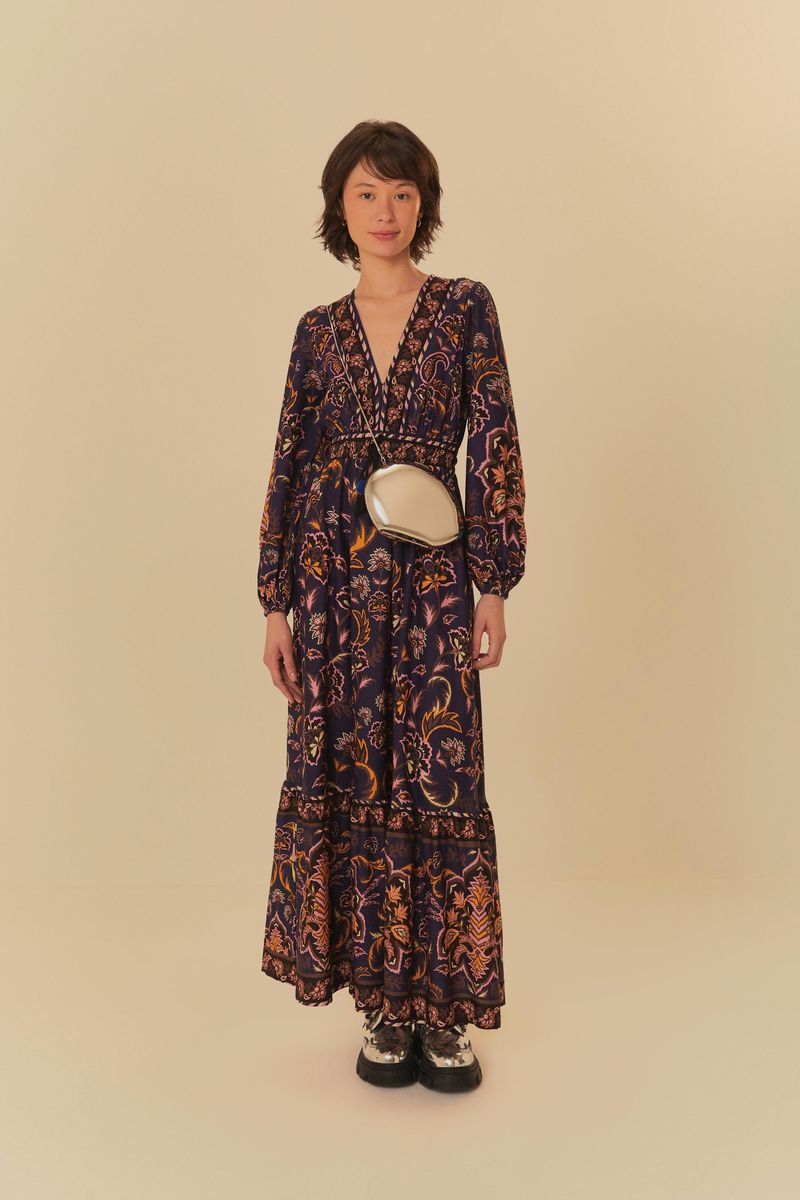 Vestido largo estampado con escote en V y mangas largas, mostrado con bolso cruzado.