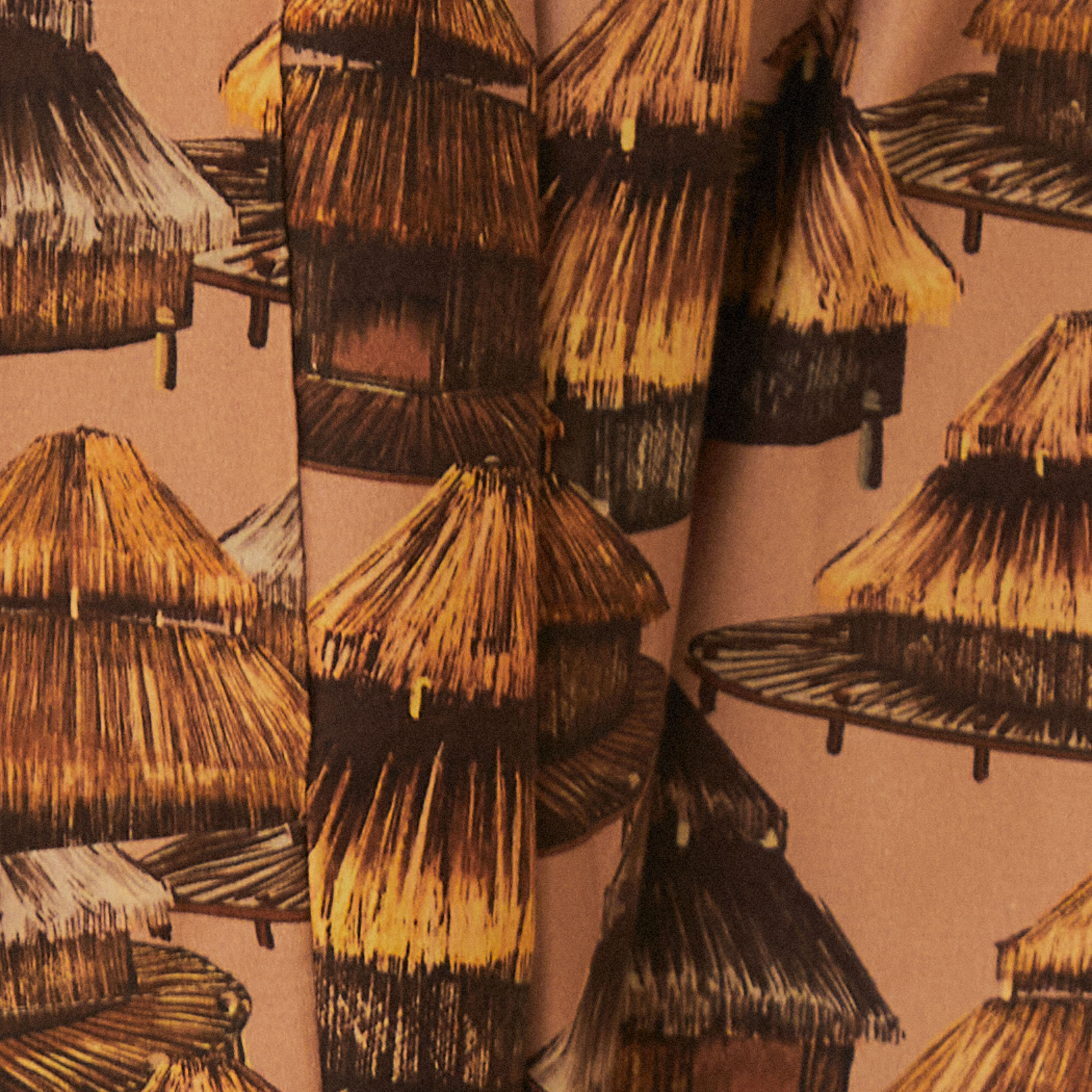 Detalle-de-la-estampado-tropical-en-el-pantalon-mostrando-cabañas-y-palmeras-en-tonos-terrosos.