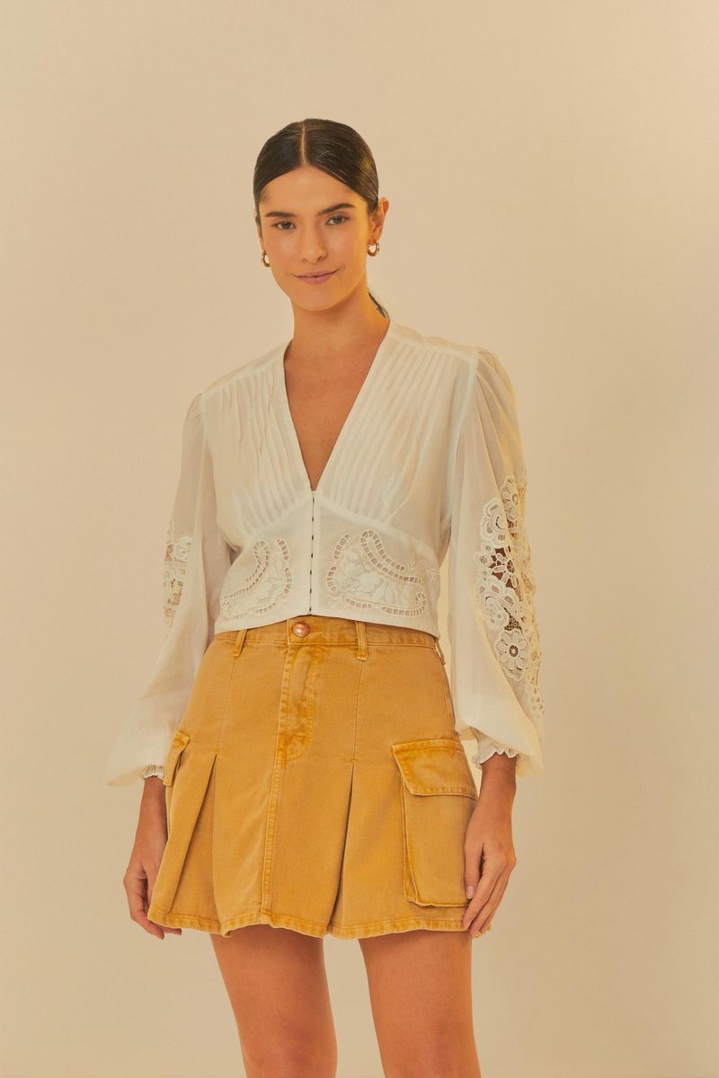 Modelo-usando-falda-mostaza-con-pliegues-y-bolsillos-cargo-combinada-con-blusa-blanca.