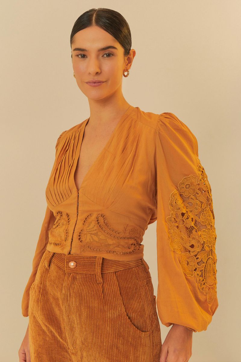Blusa romántica bordada en tono terroso con escote en V y mangas amplias decoradas con bordados artesanales, vista frontal.