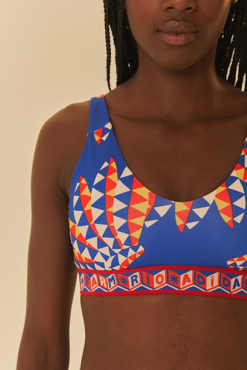 Detalle del top deportivo Adidas con estampado geométrico vibrante, mostrando el ajuste y diseño.