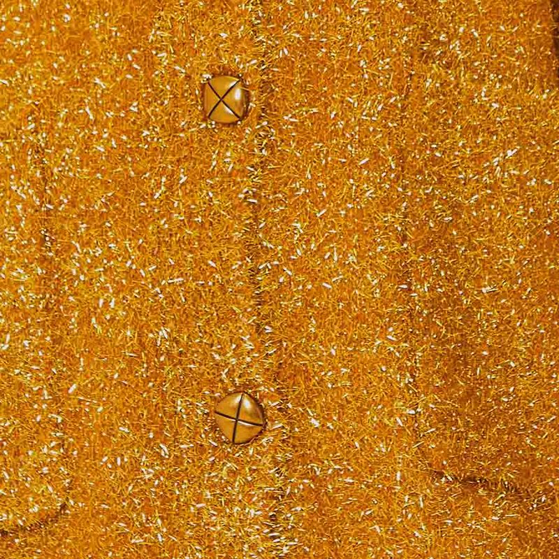 Close-up de la textura del tejido y los botones del suéter dorado.