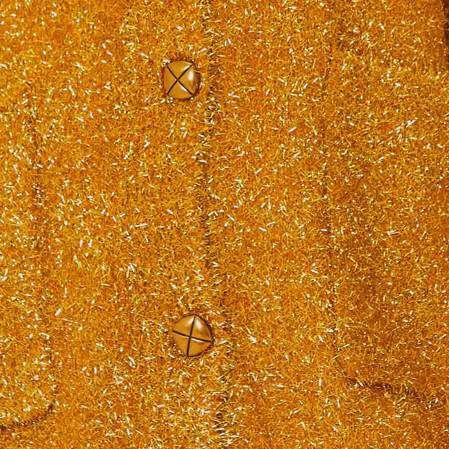 Close-up de la textura del tejido y los botones del suéter dorado.