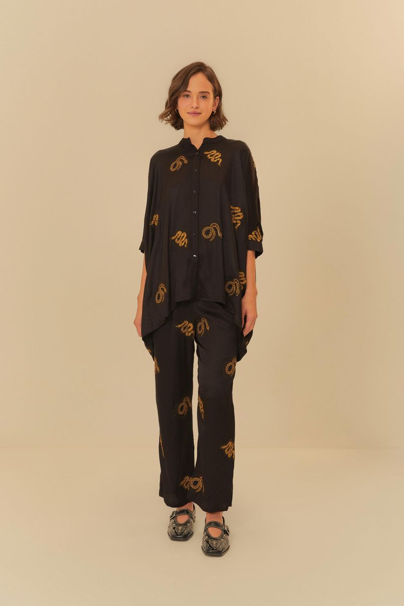 Modelo-vistiendo-conjunto-de-pantalon-y-camisa-negra-con-bordados-dorados.