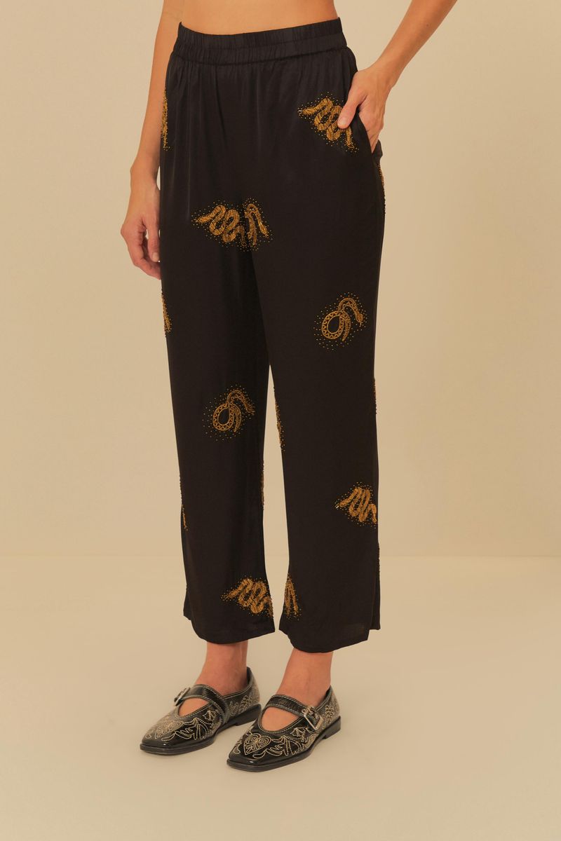 Vista-frontal-del-pantalon-negro-con-bordados-dorados-de-serpiente.