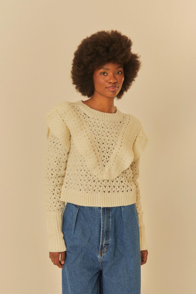 Vista frontal de un cárdigan de tricot beige con textura floral y detalles en los hombros.