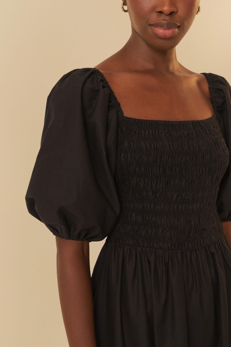 Vista trasera del vestido negro con bordados coloridos en la falda y mangas abullonadas.