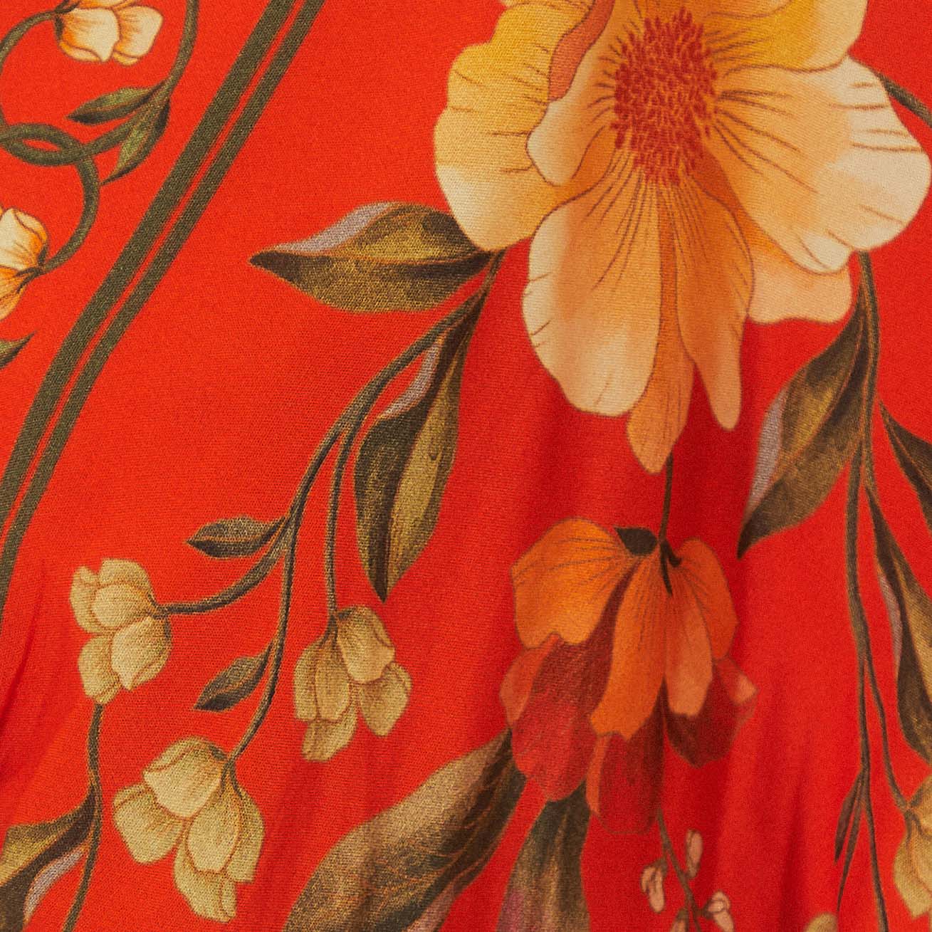 Acercamiento del estampado floral vibrante del vestido sobre fondo rojo.