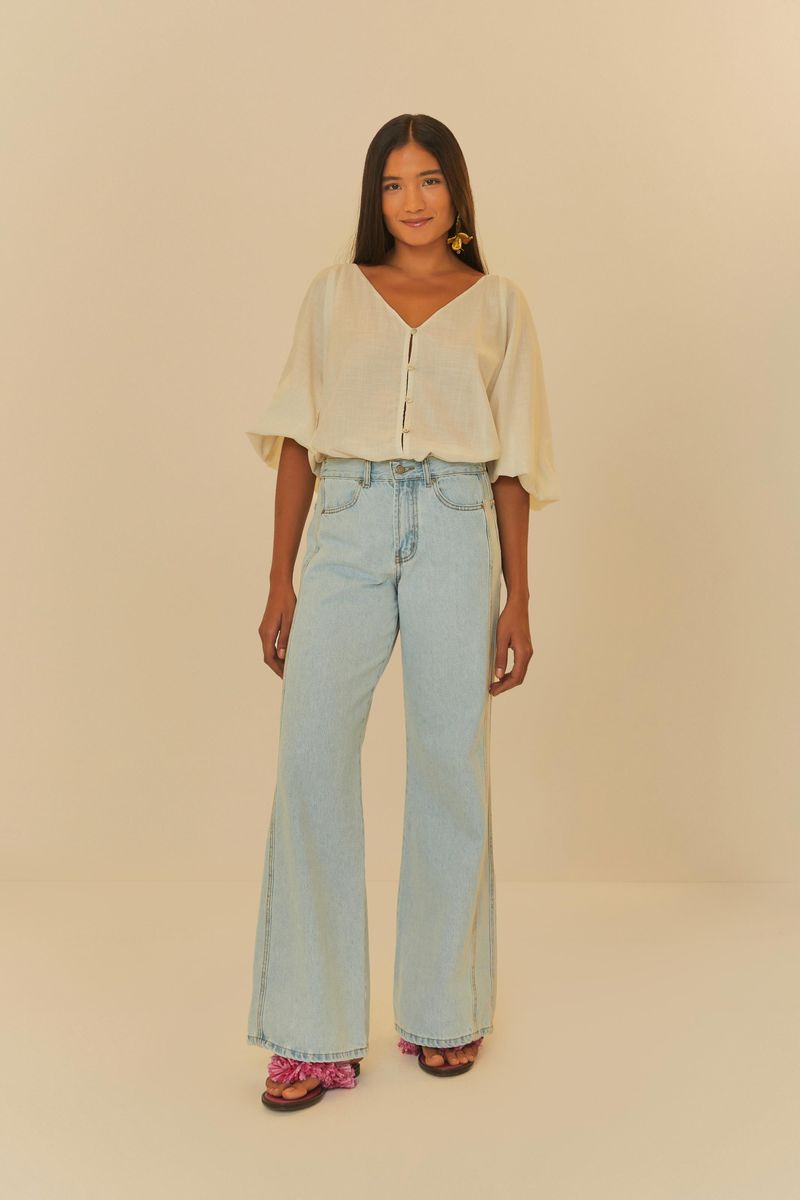 Modelo-usando-pantalon-en-mezclilla-azul-claro-con-blusa-blanca-de-mangas-amplias.