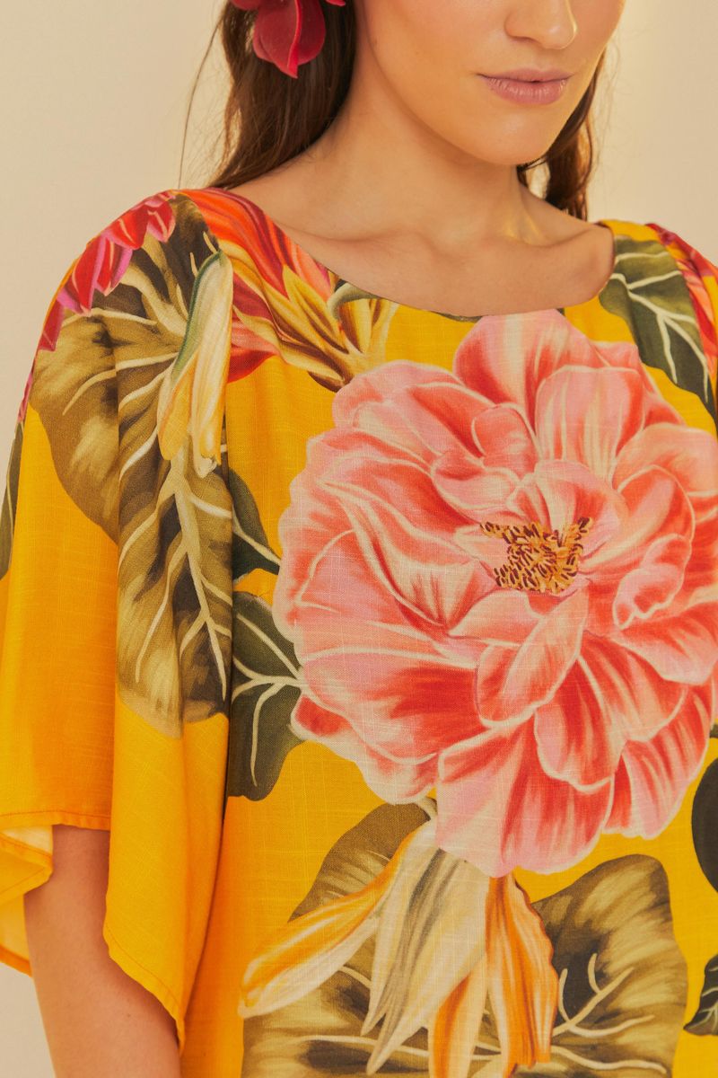 Primo plano del tejido del vestido mostrando el diseño floral y botánico sobre fondo amarillo.
