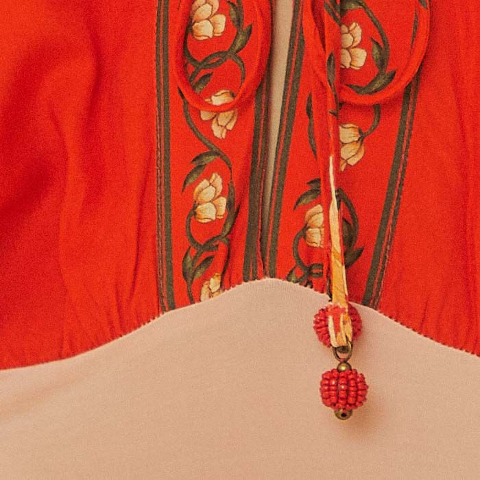 Primer-plano-del-cordon-decorativo-en-el-escote-del-body-floral-rojo.