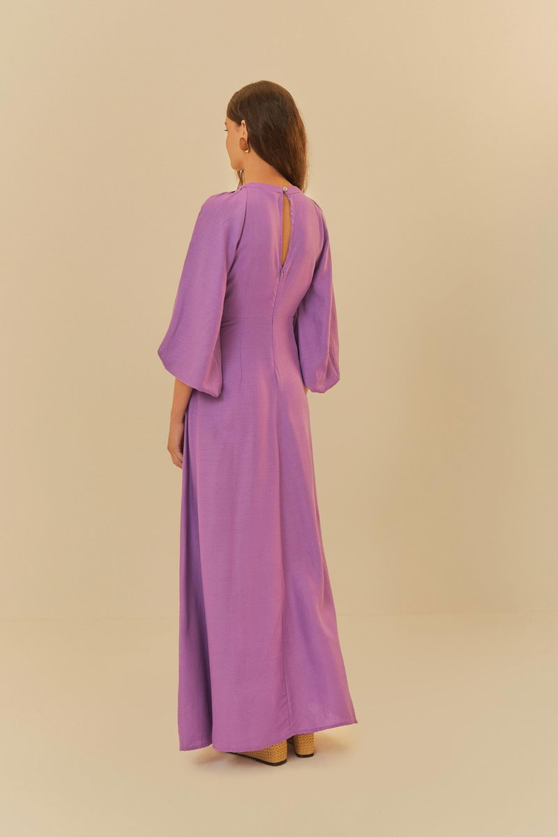 Vista trasera del vestido morado, destacando el cierre discreto y el diseño de las mangas amplias.