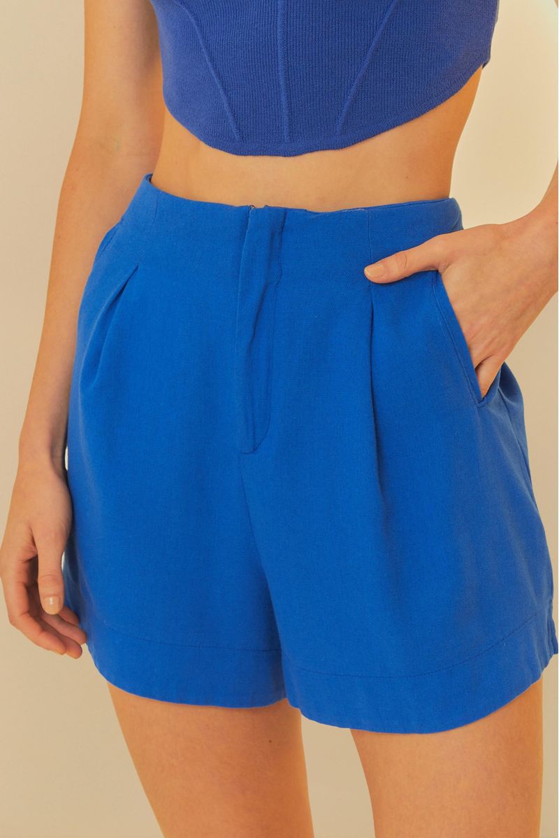 Close-up del short azul mostrando los detalles de los bolsillos y de la cintura alta.