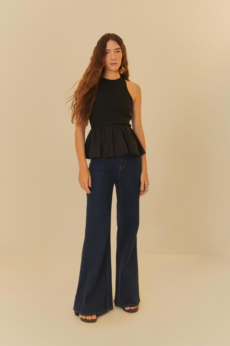Modelo luciendo pantalón jeans flare azul intenso con blusa negra sin mangas.